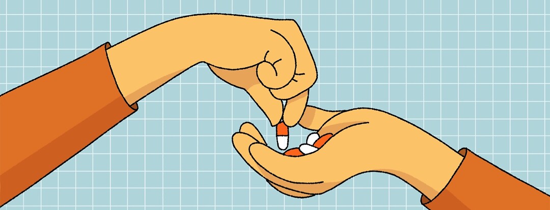 A hand picks a single pill out of a pile of pills