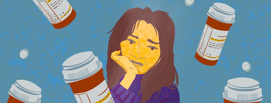A woman looks sadly at bottles of prescription pills