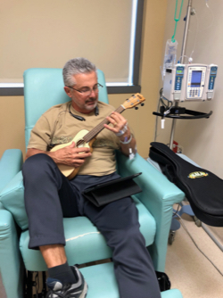 Whitney Les playing guitar while in a medical chair