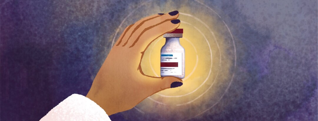 A person's hand holds a vial of medicine.