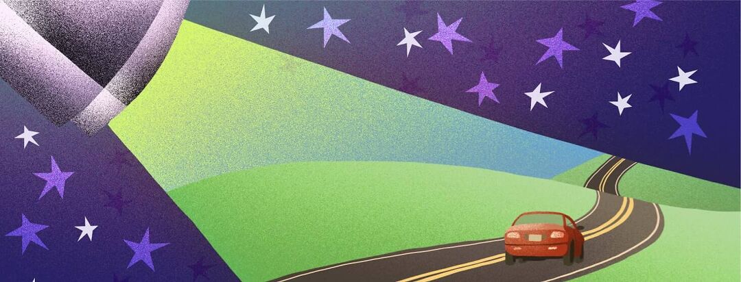 A spotlight shines on a car driving down a windy road